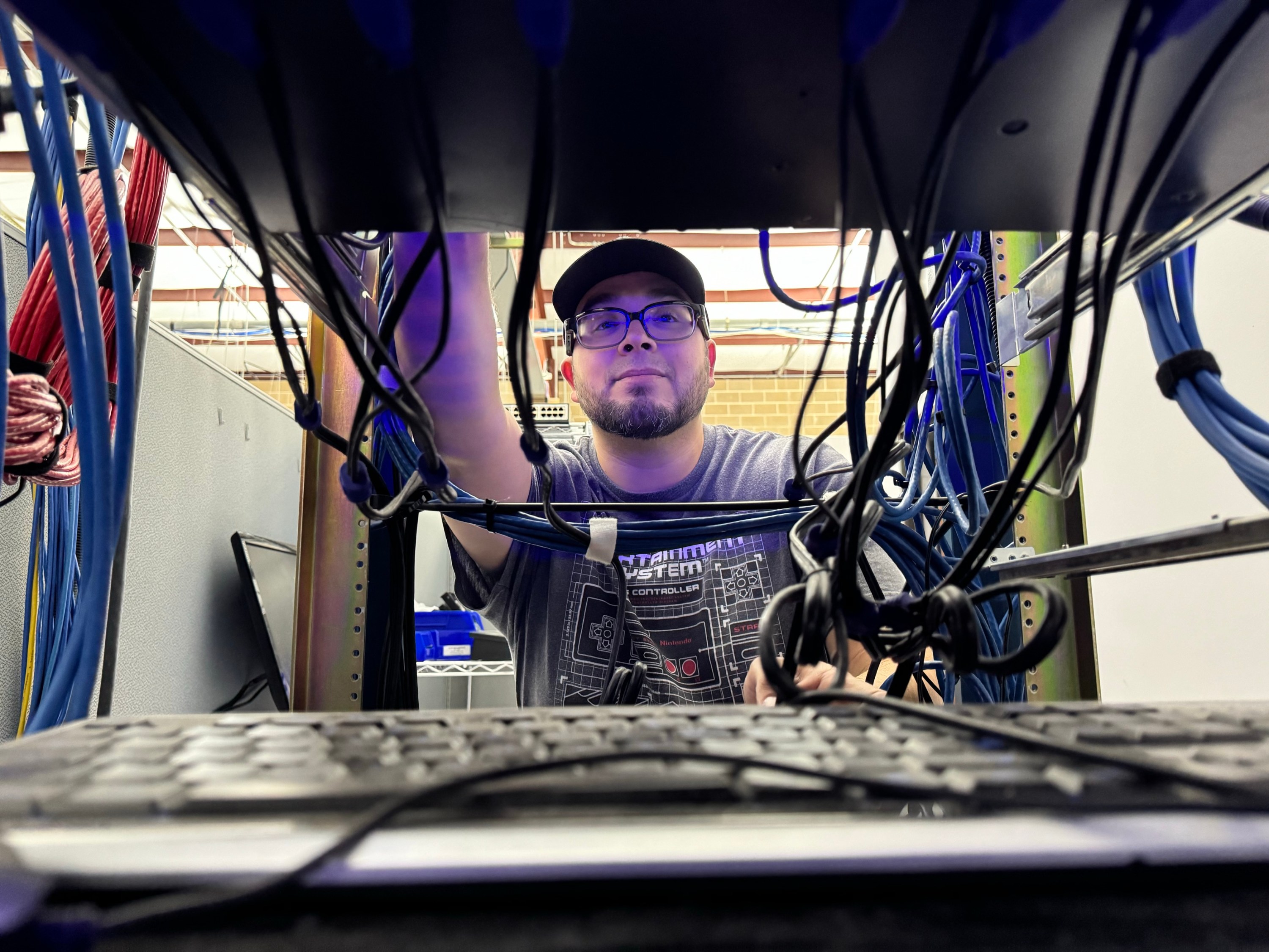 Image illustrating careers NDI, a collaborator is standing behing a server rack.